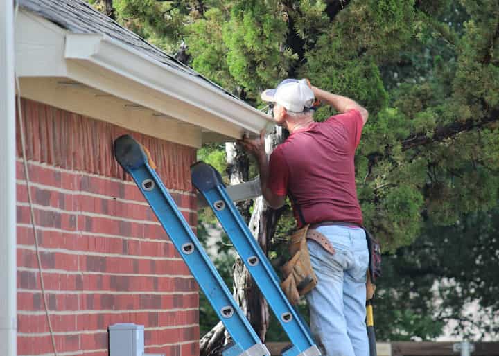 Roofing maintenance experts attach new gutters on a home in Pacific Palisades, CA